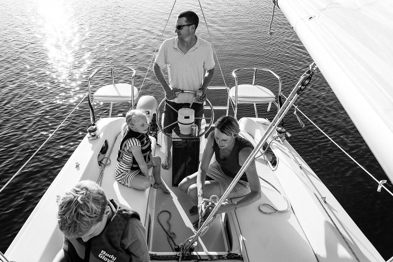 Black adn white. Top down view of family on a sailboat at sunset.