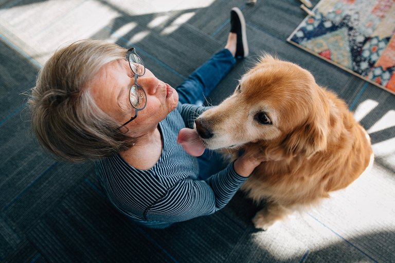 Grandma and senior golden retriever kiss the air at the same time. Overhead view. 