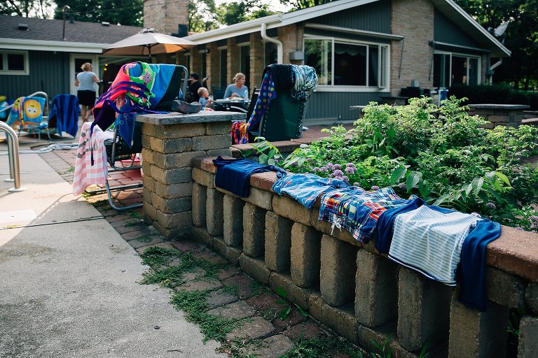 Wet swim suits line the brick wall at the end of the day to dry. 