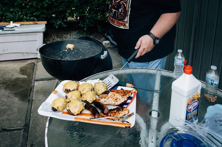 man places cheeseburgers on a platter. 