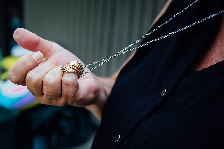 woman holds wedding bands on a necklace chain