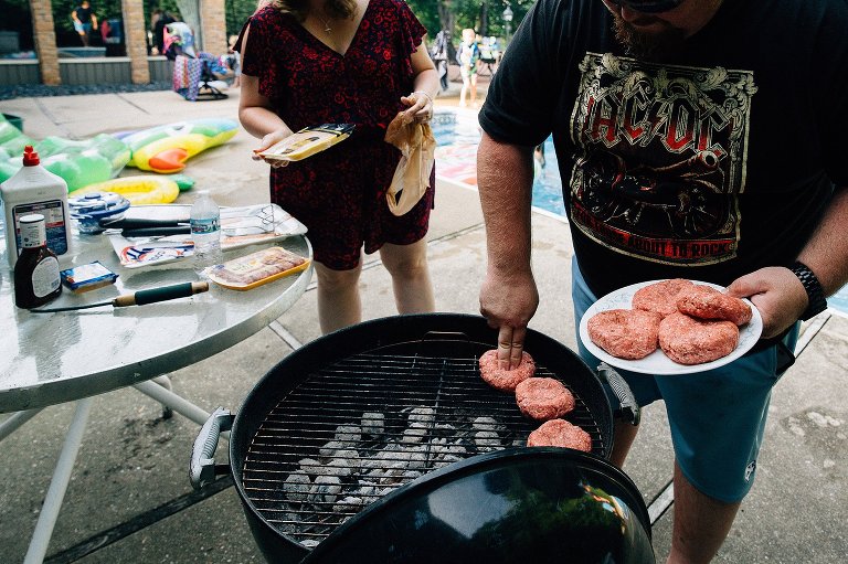 Two people prepare the grill and put burgers on