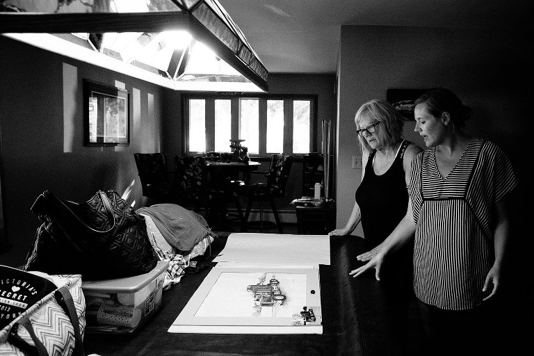 Mom and daughter look at an illustration of a truck on a pool table. 