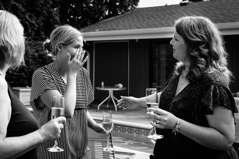 Black and white. Woman wipes away a tear while another women reaches toward her. 
