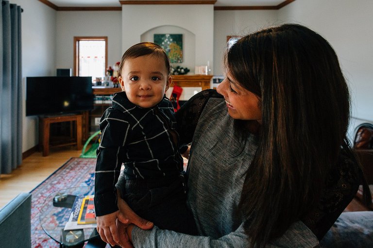 Mother smiles at 1 year old boy in a home living room. 