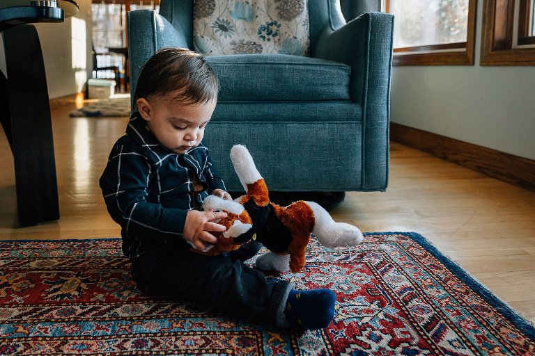 1 year old boy examines a puppy stuffed animal