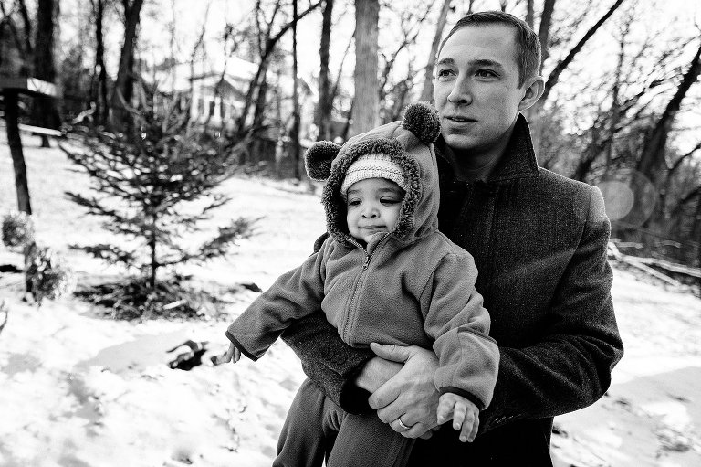 Dad and young son stand in snowy backyard. Blakc and white 