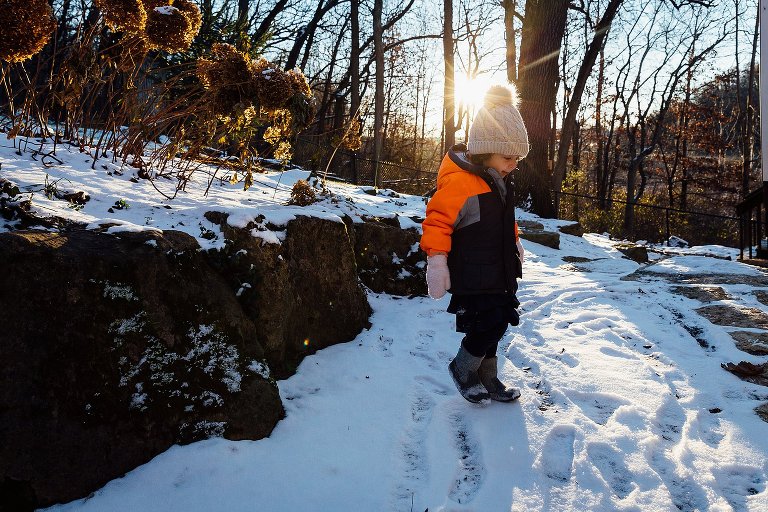 Late afternoon sun hits the top of girl's hat during a snowy walk