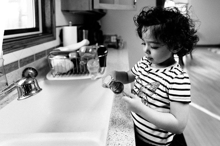 Girl plays with garlic press in the kitchen sink