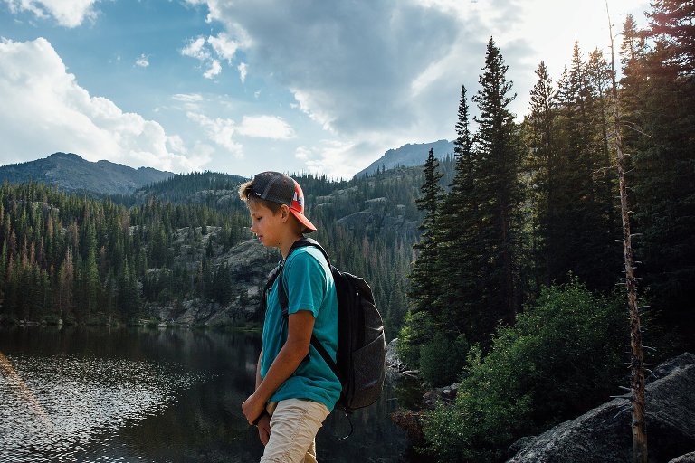 teen stands next to pond in the mountains 