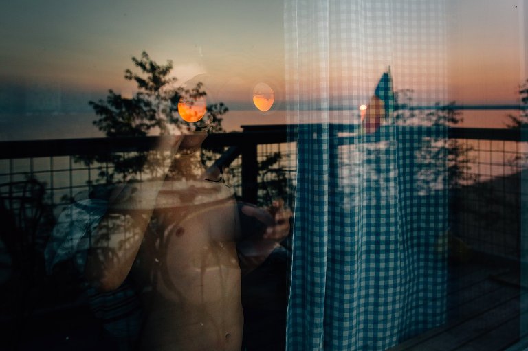 child looks through binoculars out at sunset on the lake, lake is reflected in glass 