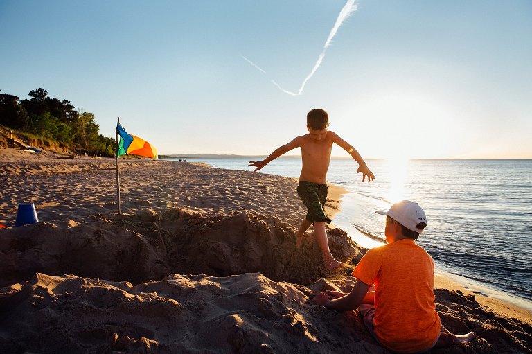boy jumps over a sand trench next to lake 