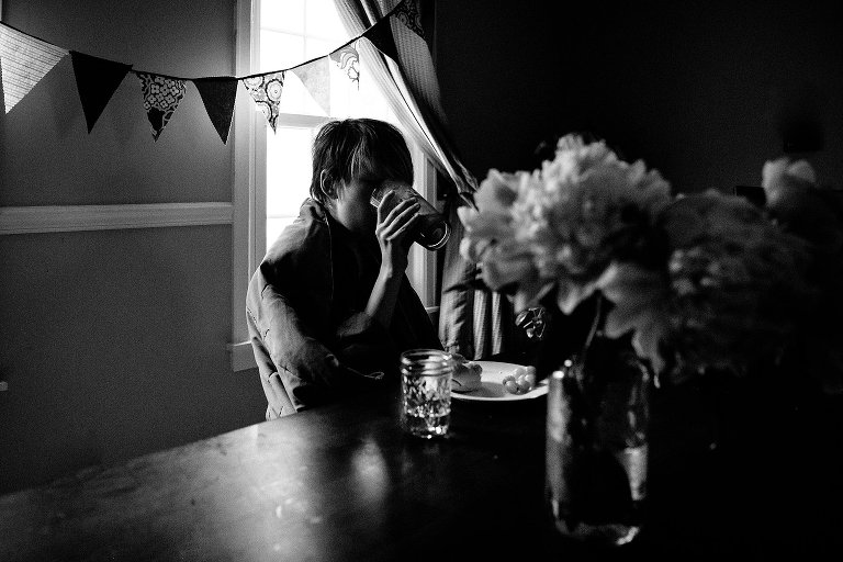 black adn white. boy drinks from a glass in low light. 