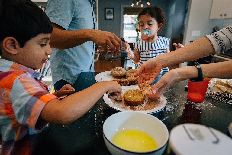 4 family members dip donuts in butter and roll in cinnamon sugar mixture 