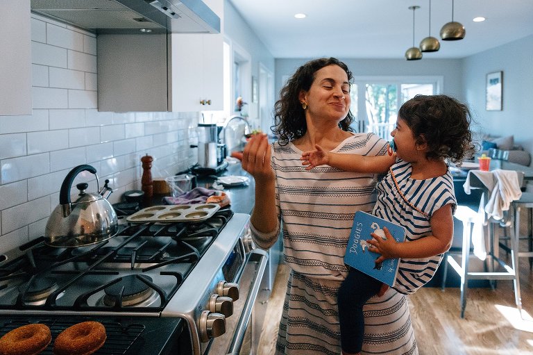 Mom and daughter dramatically use their hands to waft the air of freshly baked donuts toward them