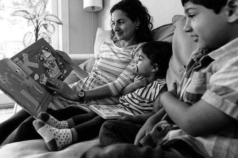 Black and white. Mom reads a book to 2 kids on the couch during a Madison family photographer session
