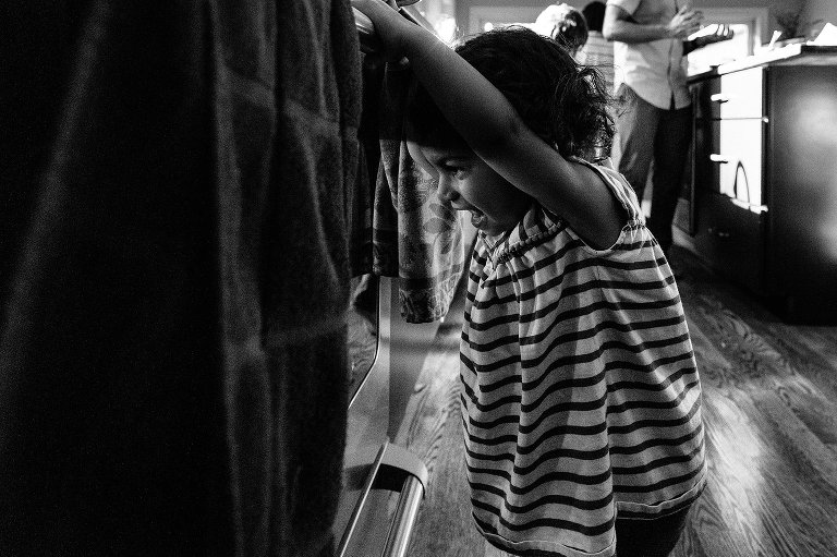 black and white. daughter illuminated by the oven light as she checks on the baking donuts during a Madison family photographer session
