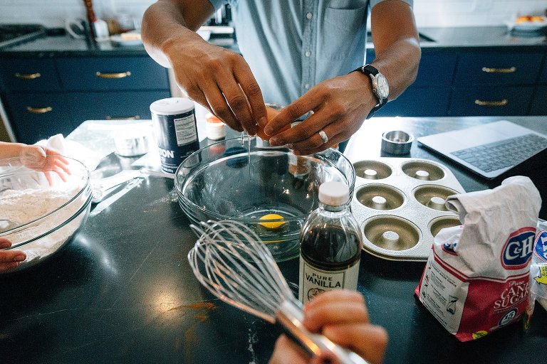 Male hands crack an egg in a glass bowl during a Madison family photographer session