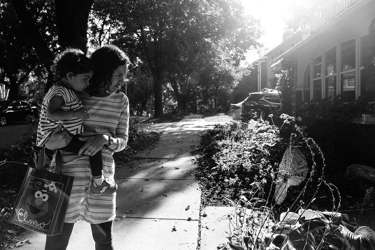 Black and white. Mom and daughter explore a large spider web illuminated in the sun during a Madison family photographer session. 