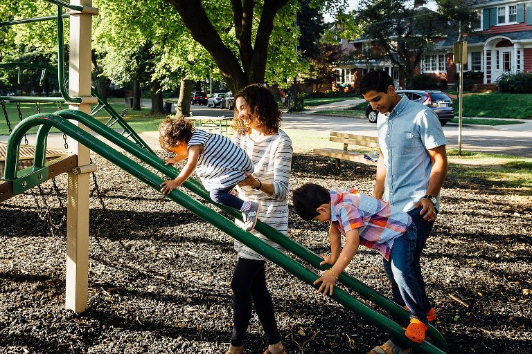 Mom and Dad support their two children on playground equipment during a Madison family photography session