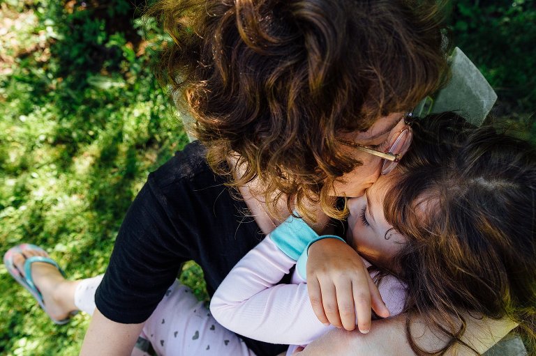 Mom kisses daughter on top of the head, top down view 
