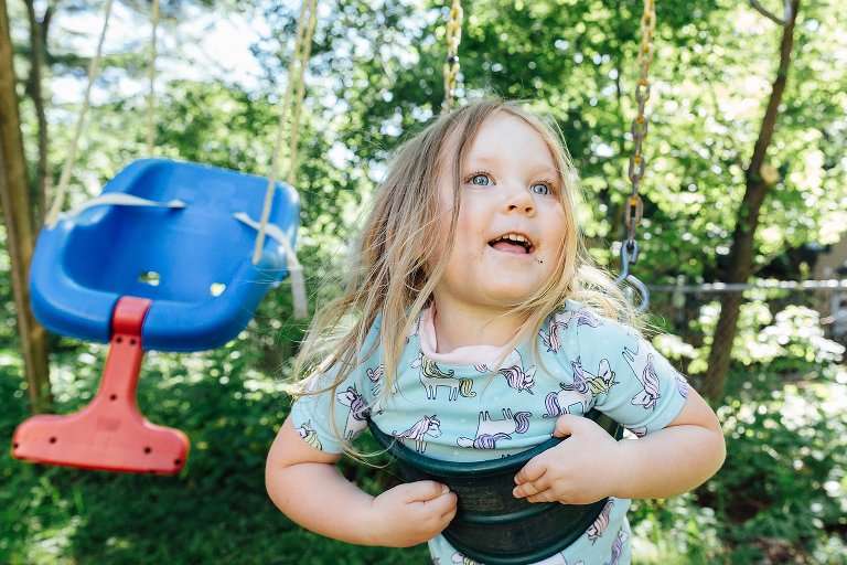 Girl smiles on swing in her backyard