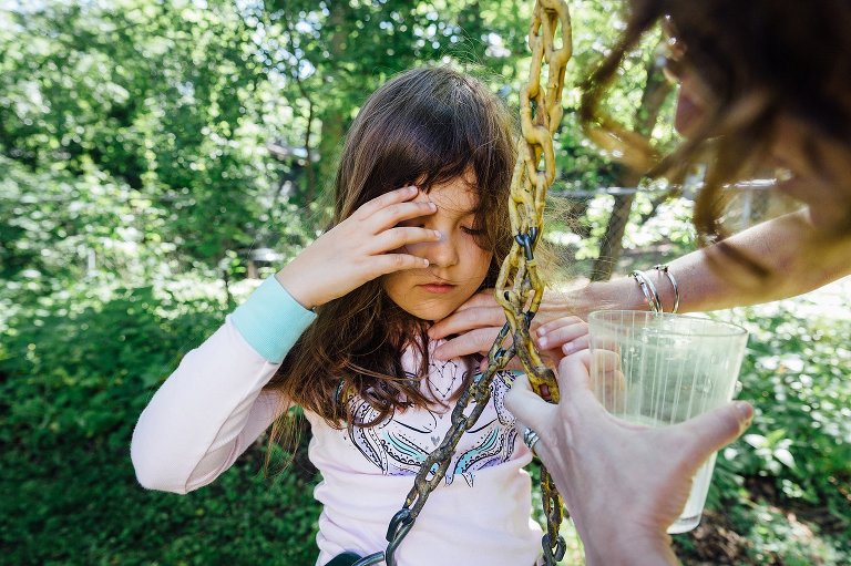 Girl spins on swing ang gets hair tangled, Mom helps fix