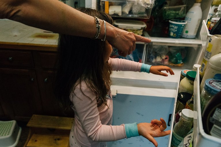 mom points as daughter reaches into refrigerator 