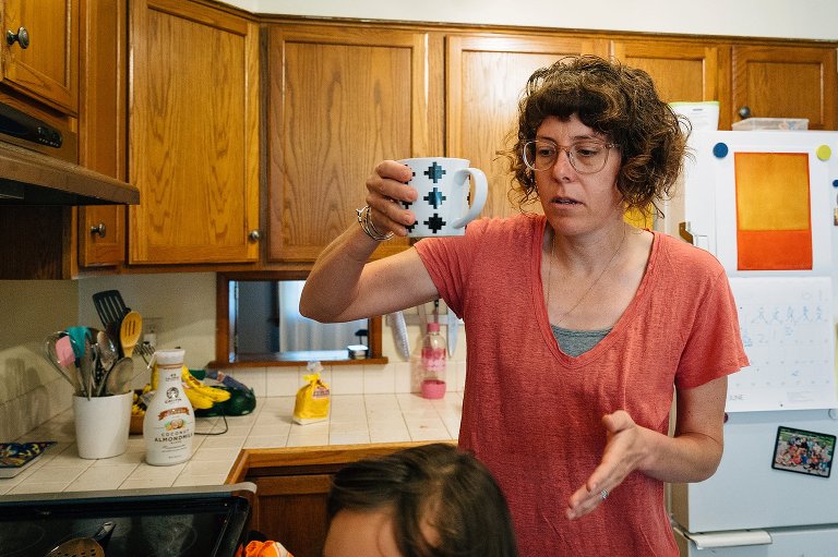 mom lifts coffee cup carefully over child's head 