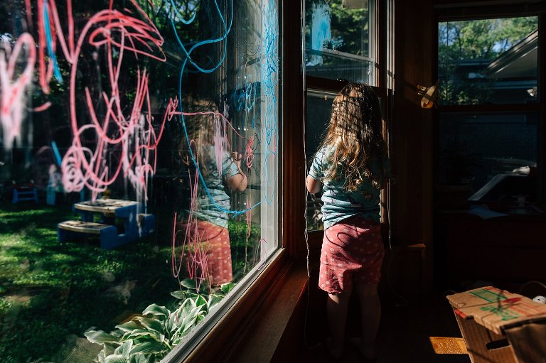 Girl stands in window with marker shadows 
