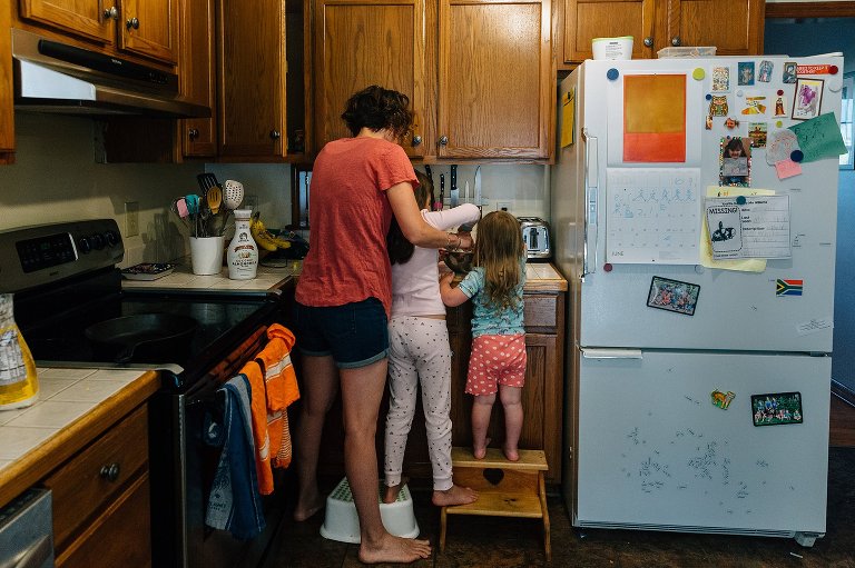 Mom and two daughters stand at kitchen counter making pancakes on a spring Saturday morning