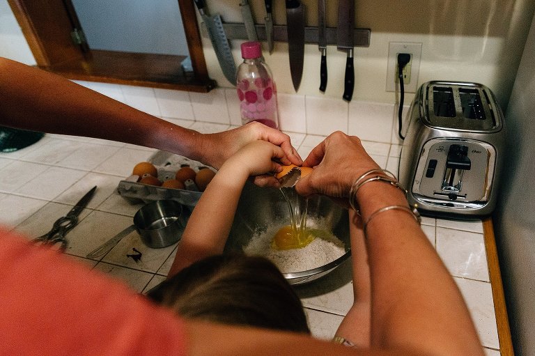 Hands crack an egg over steel bowl