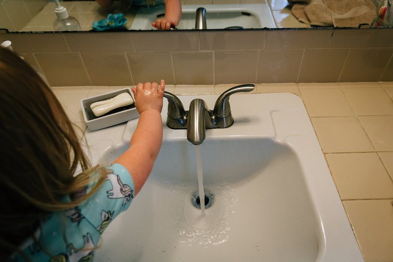 Girl turns off faucet after washing hands. 
