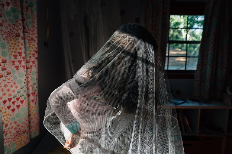 girl is under bed net in morning light 