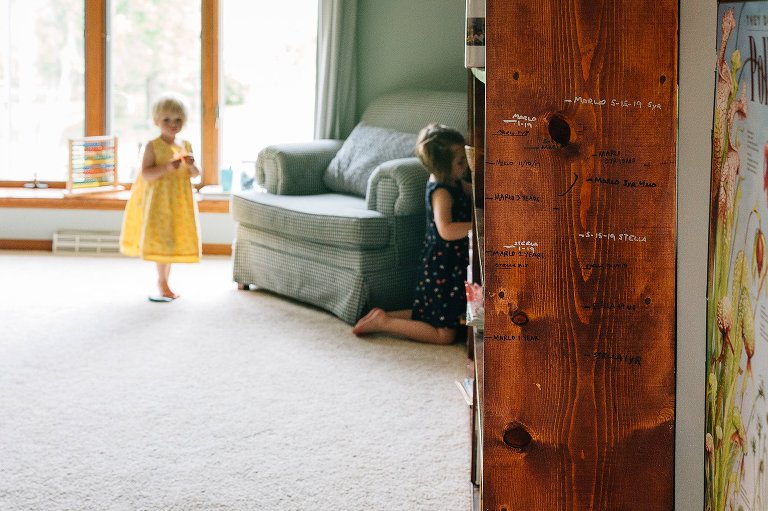 Focus on growth chart on side of bookcase with two young girls in the background