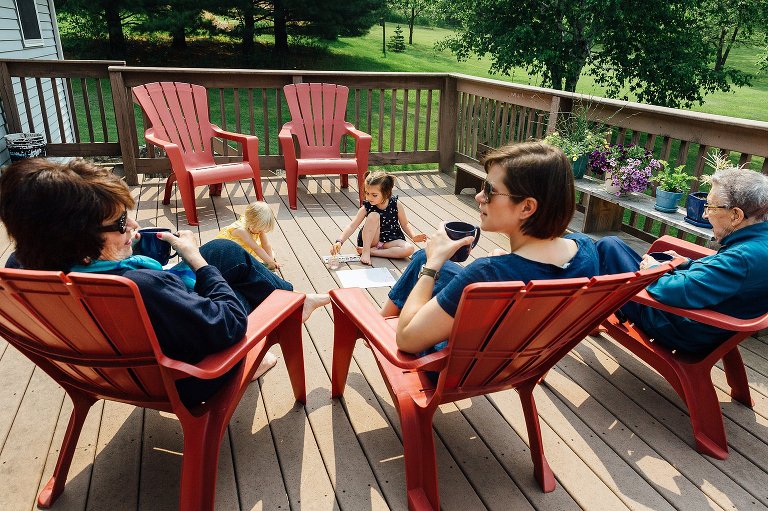 Four generations of women gather on a porch on a sunny day