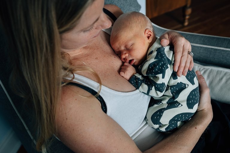 mom holds sleeping newborn at home 