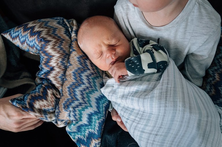 mom props a pillow under newborn while preschooler holds 