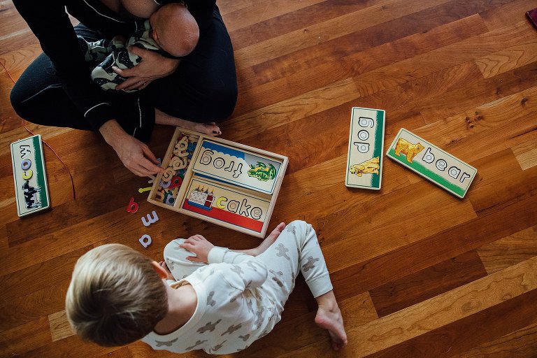 woman nurses baby while playing a puzzle with preschool child 