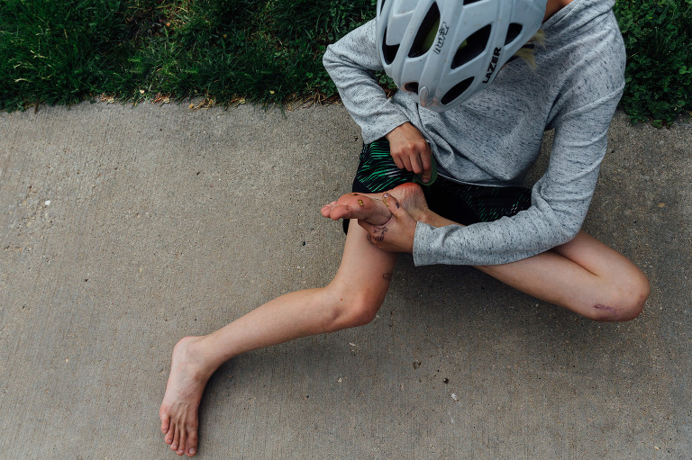 Top down view of child inspecting his dirty feet on the sidewalk 