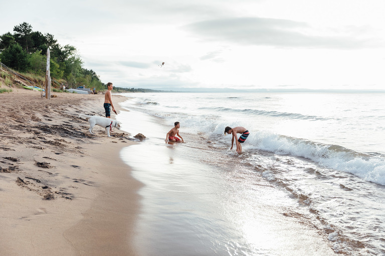Three boys and a dog play on a deserted beach. 
