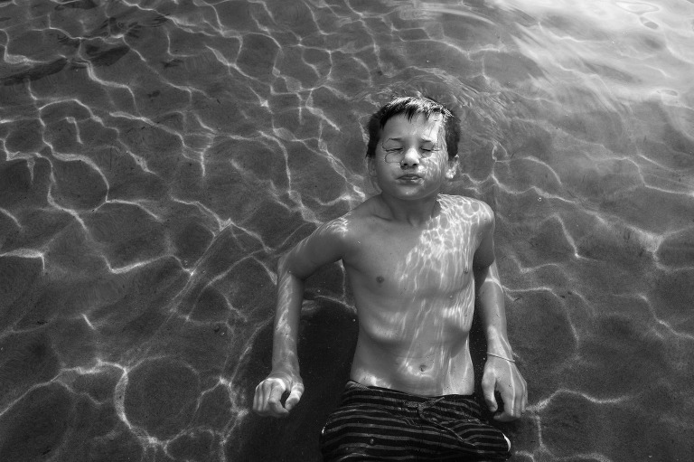 black and white, boy floats in lake