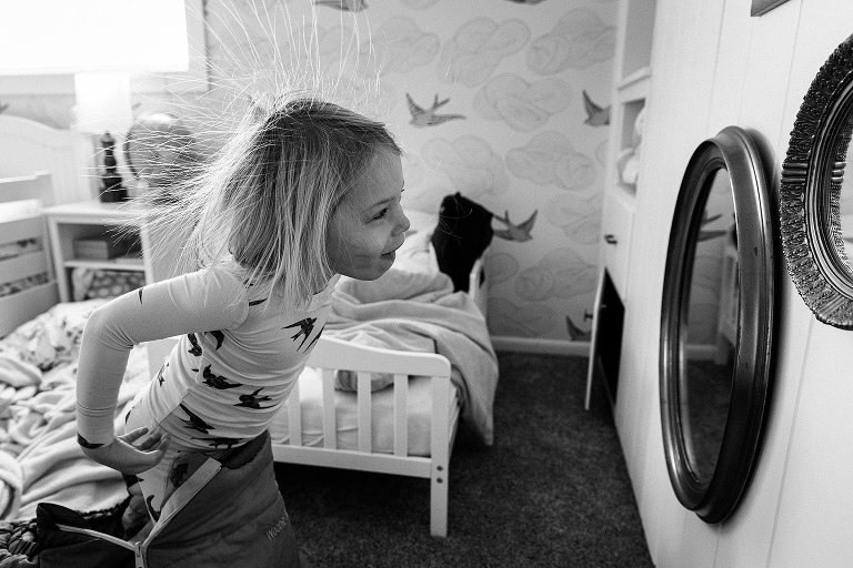 Girl checks out her static electricity hair in the mirror and smiles. 