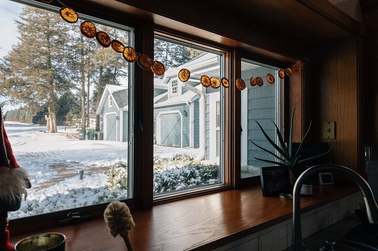 Detail shot of dried sliced oranges hanging in the kitchen window. Snowy scene outside. 