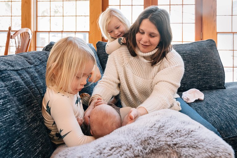 Mom and 3 sisters sit on a couch on a winter's day.