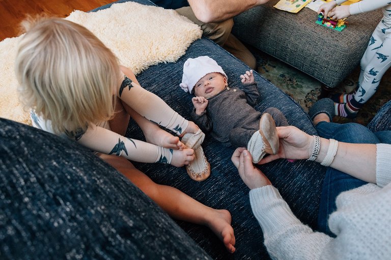 Toddler tries putting newborn shoes on her own feet. 