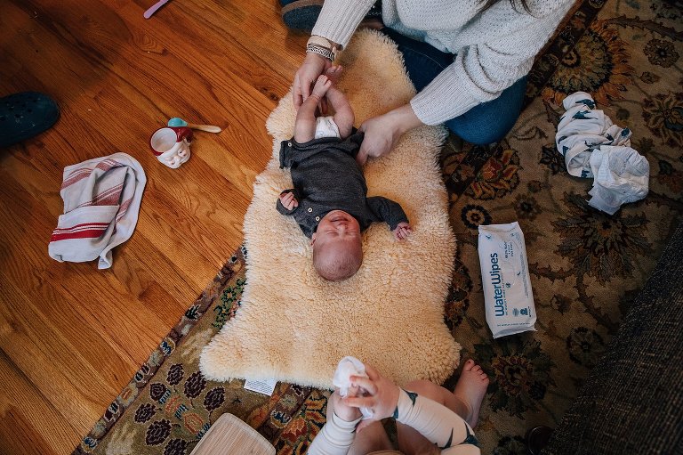 Top down view of newborn getting a diaper change and toddler washing her hands.