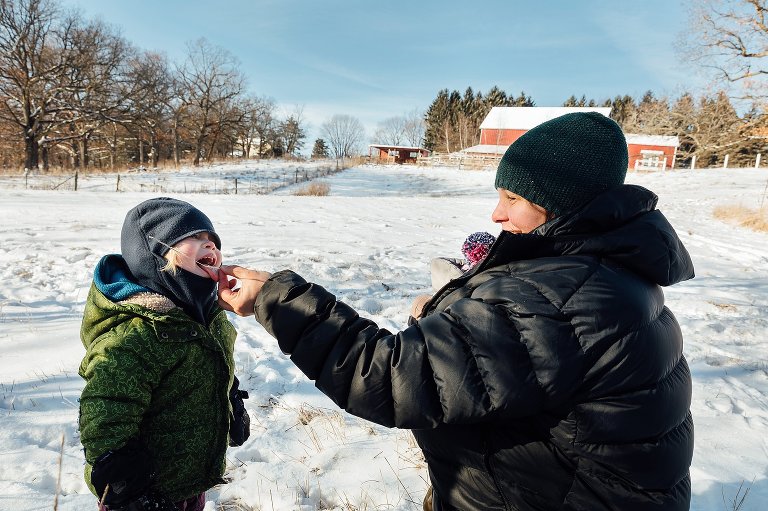 Mom holds a reed with hoar frost for daughter to lick. 