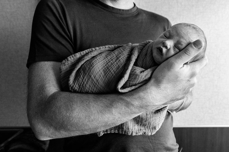Black and white. Dad holds sleeping newborn. 