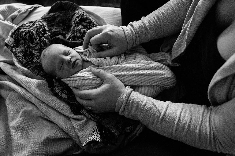 Black and white. Mom adjusts swaddle on newborn child at the hospital. 